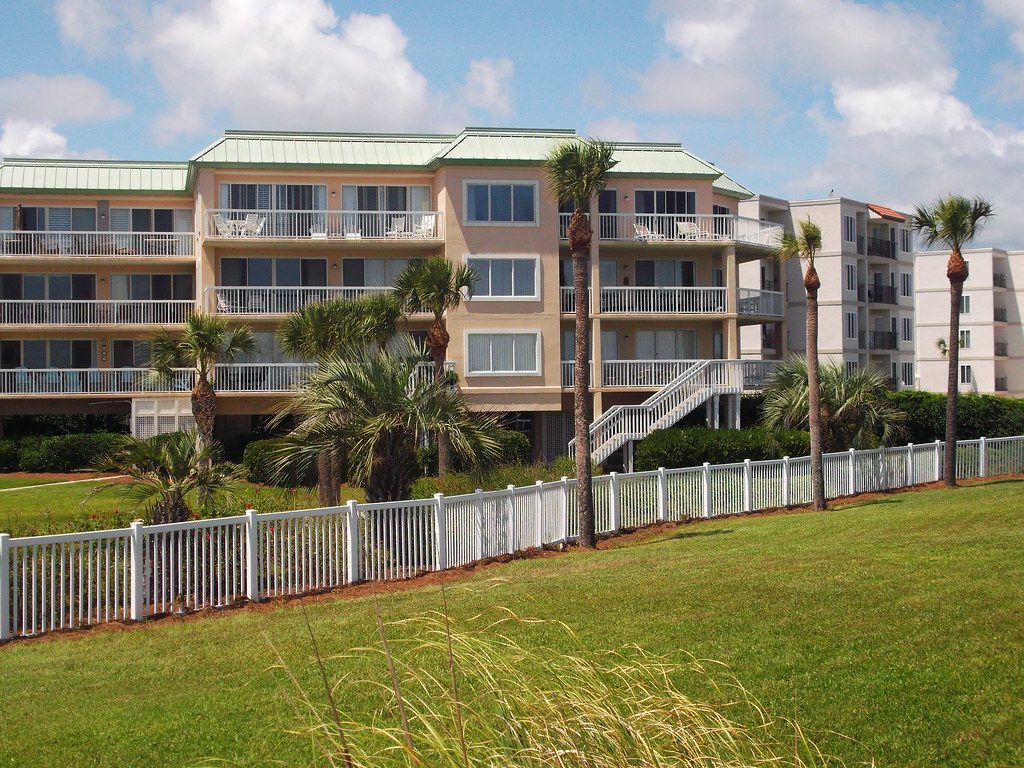 A St. Simons Island condominium community — balconies, palms, and a white picket fence along the lawn